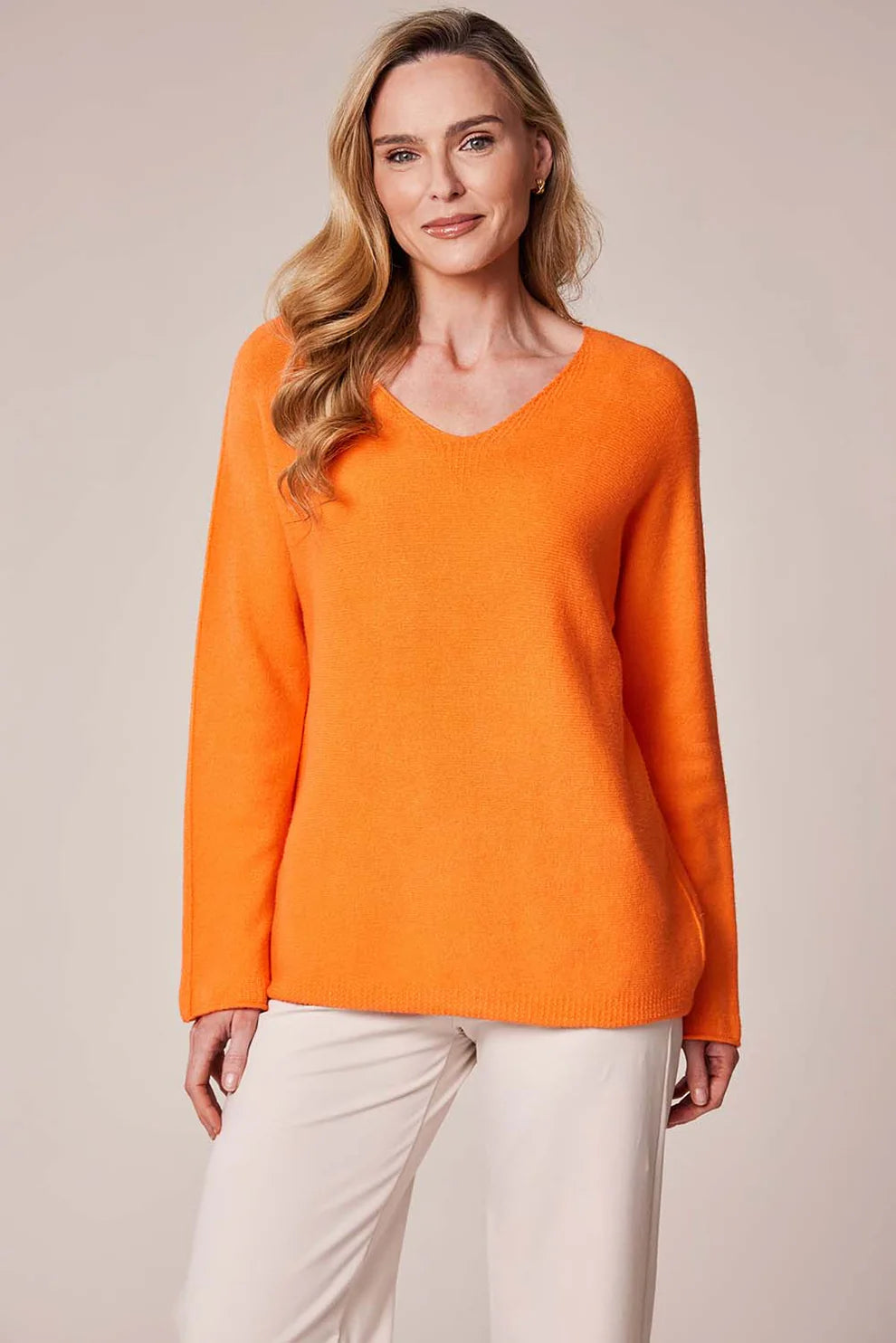 Woman wearing an orange sweater and white pants