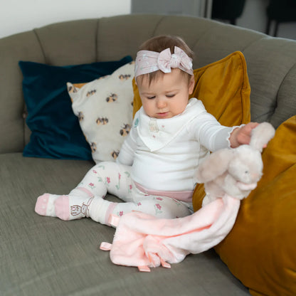 Baby sitting on a couch holding a plush toy