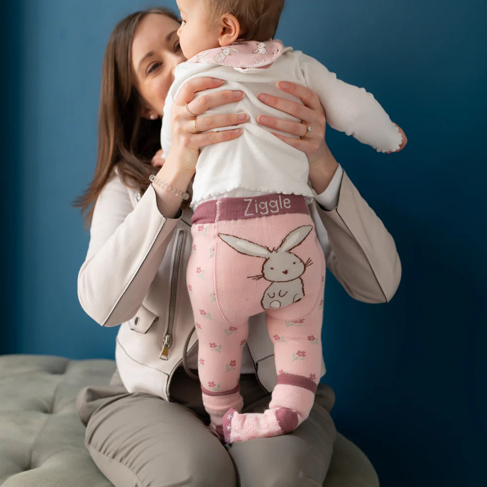 Woman holding a baby wearing pink Ziggie onesie with bunny design