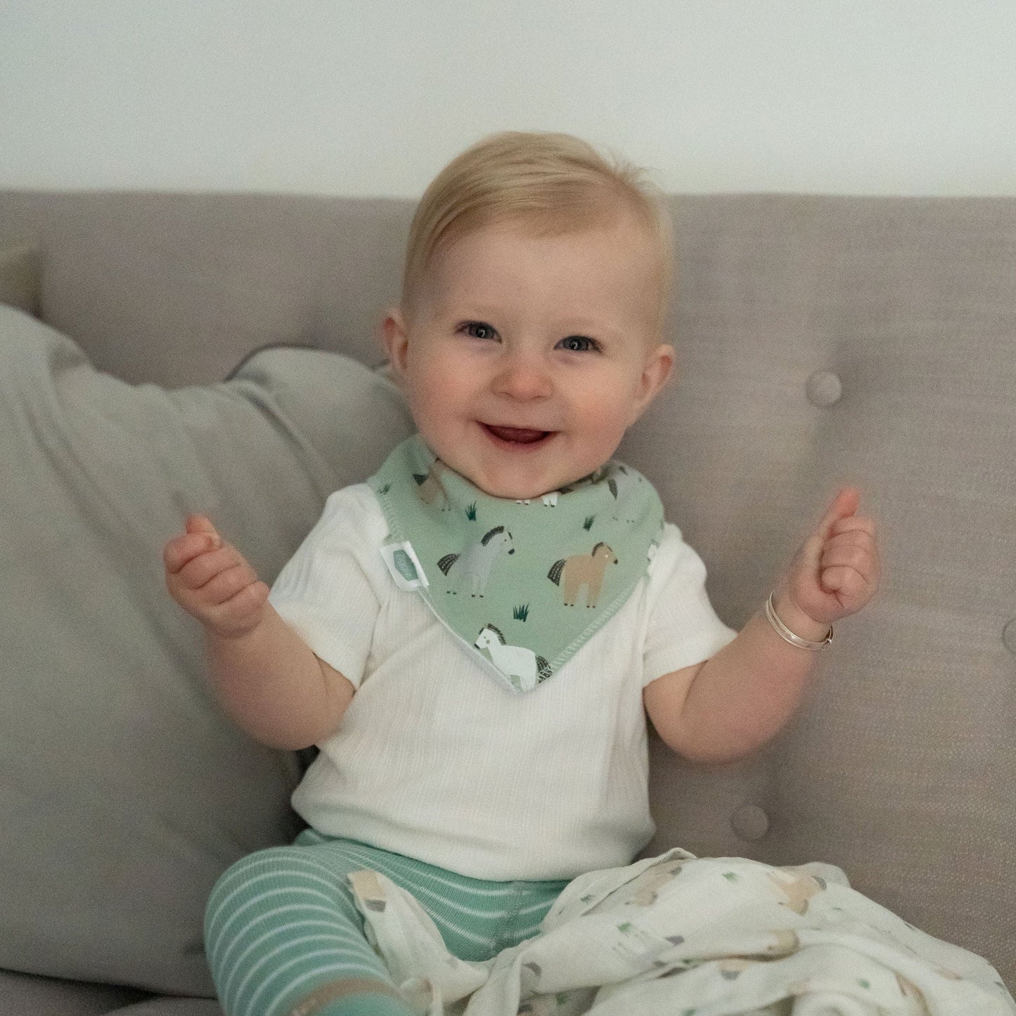 Baby sitting on a couch wearing a bib with animal patterns