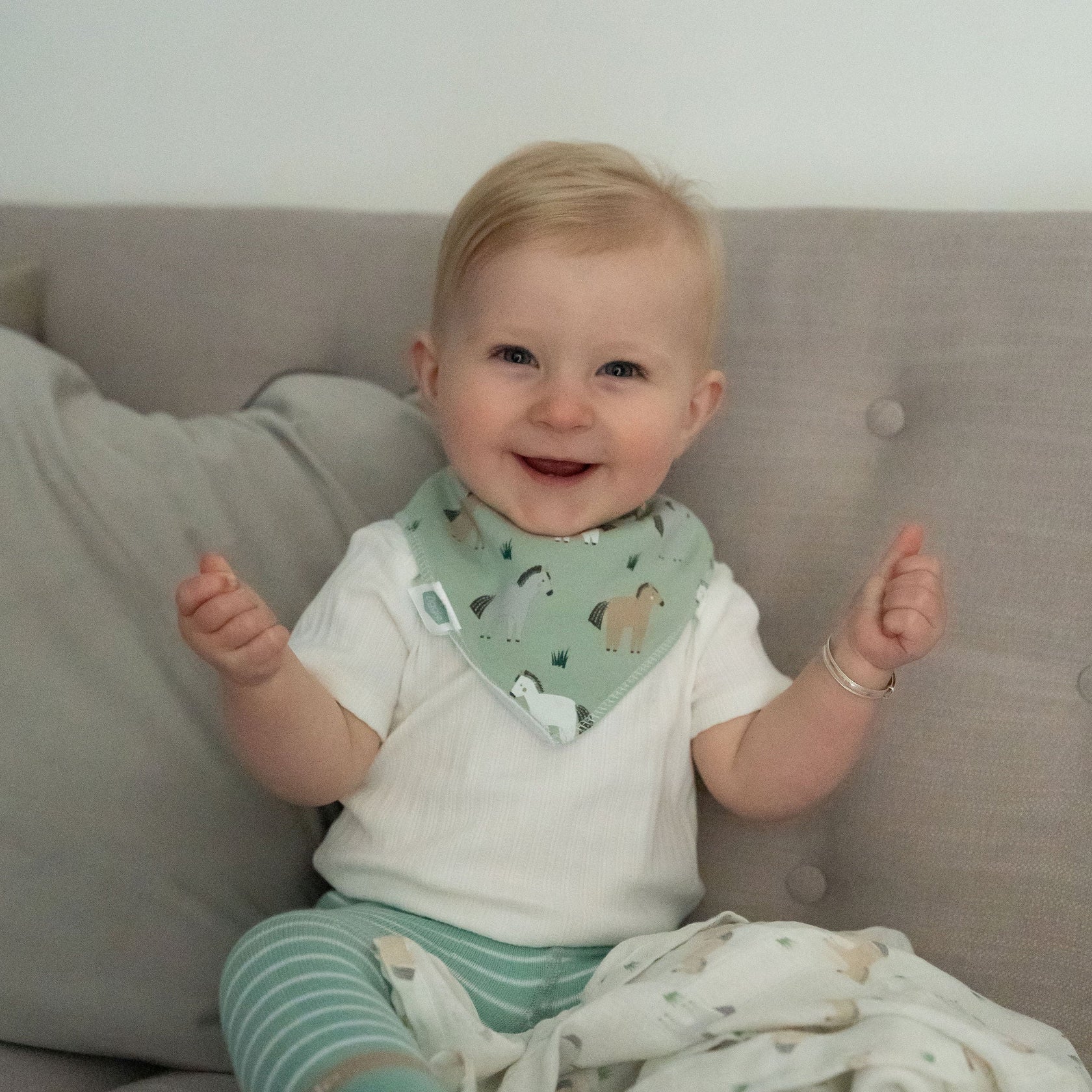 Baby sitting on a couch wearing a bib with animal patterns