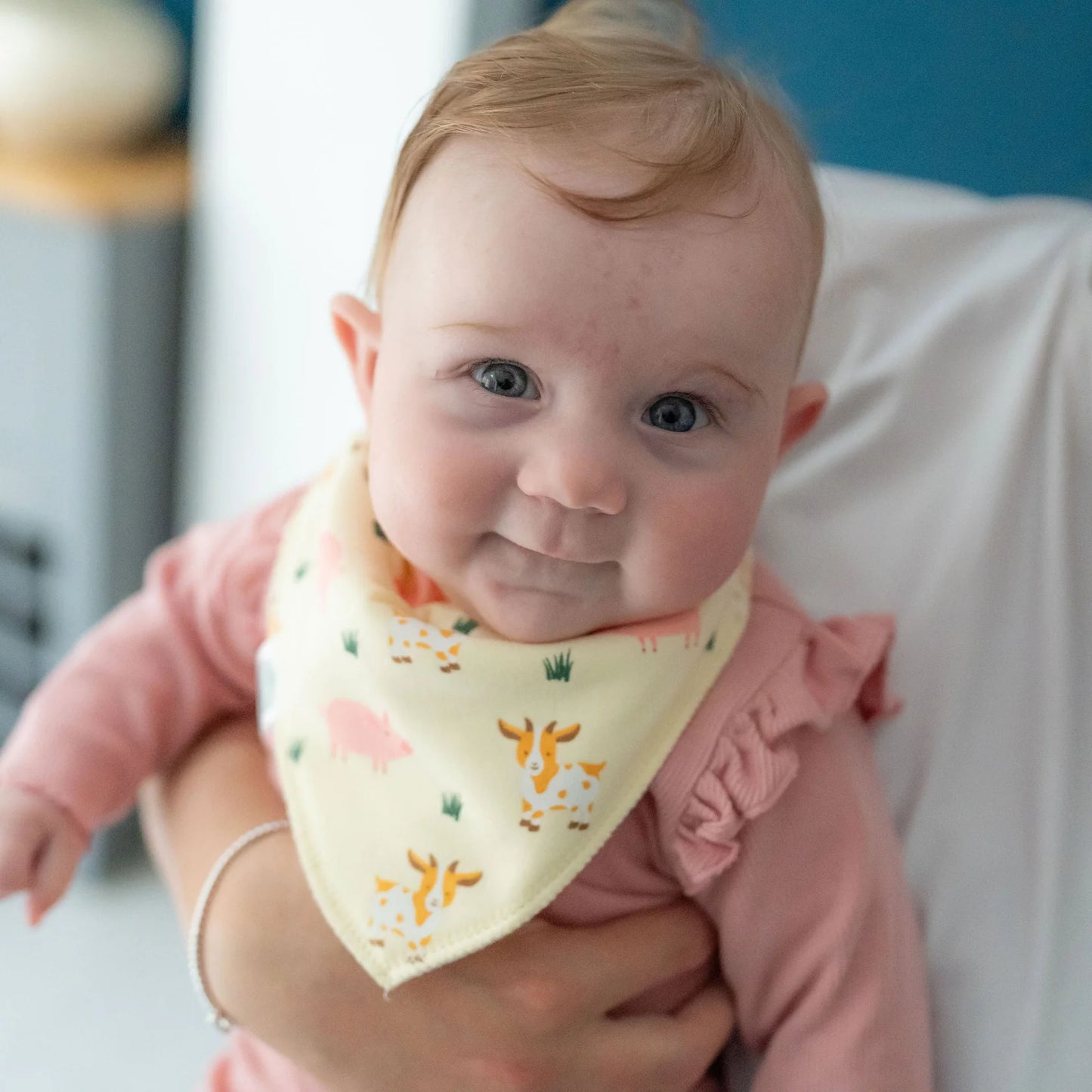 Baby wearing a pink outfit and a yellow bib with animal prints