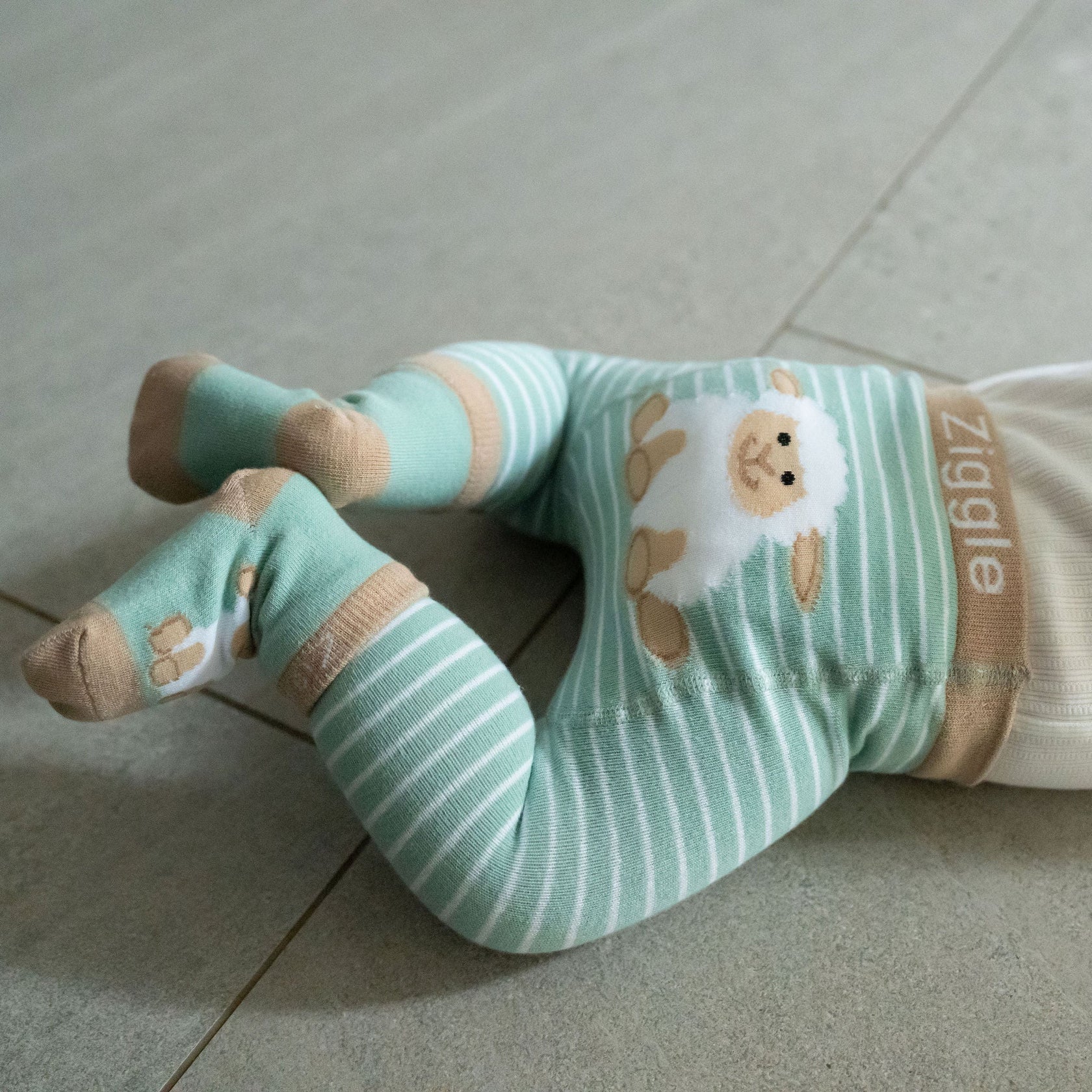 Baby legs in green and white striped socks with cartoon design