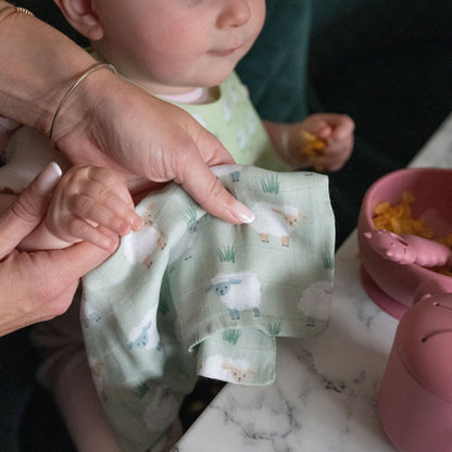 Person holding a green baby bib with animal patterns