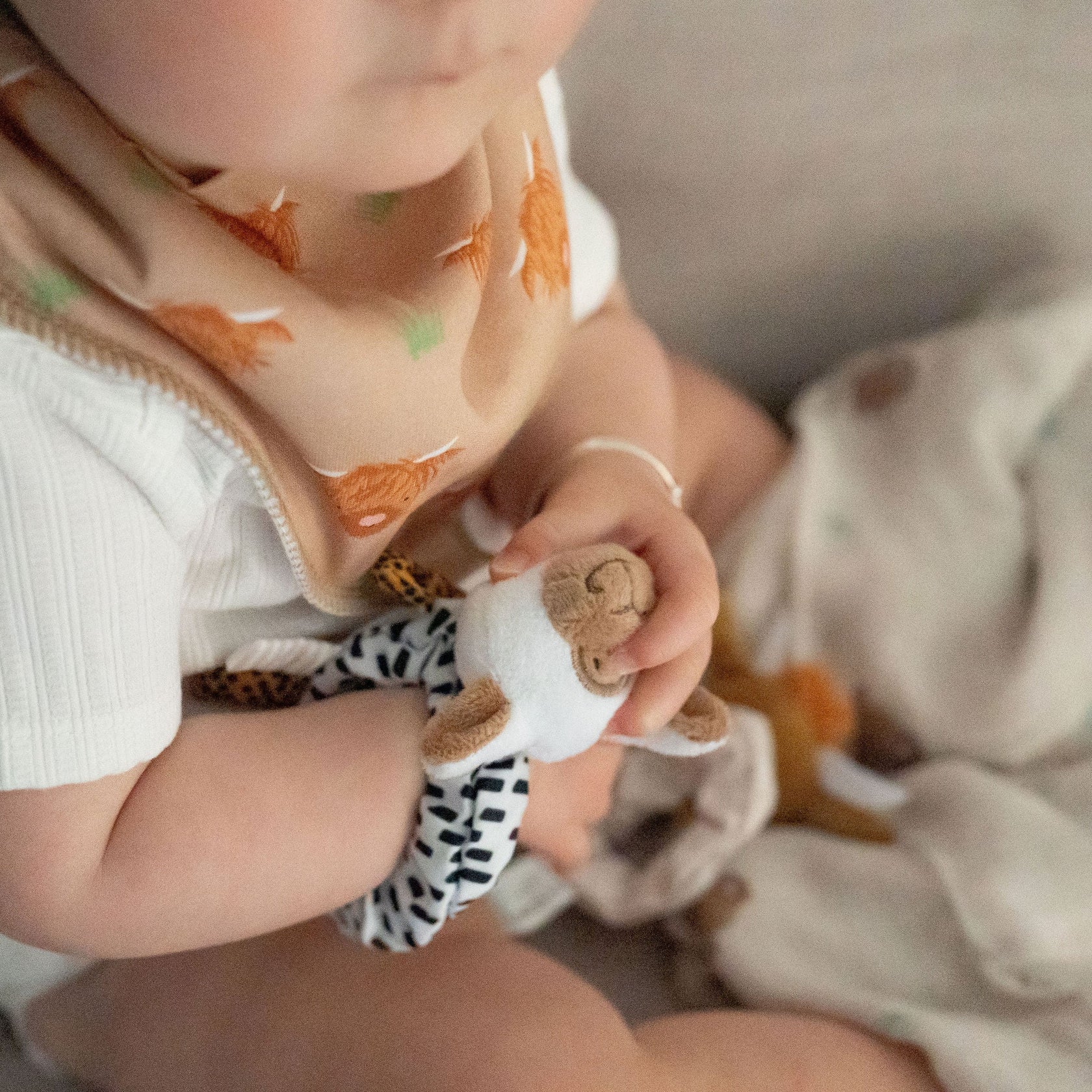 Child wearing a bib with animal prints holding a small toy