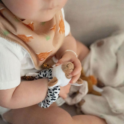 Child wearing a bib with animal prints holding a small toy