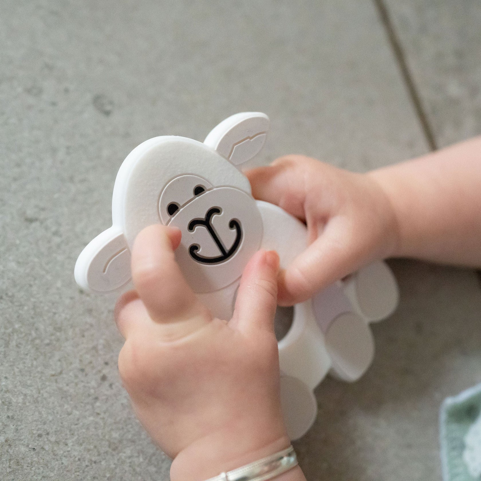 Child's hands holding a white toy with a smiley face design